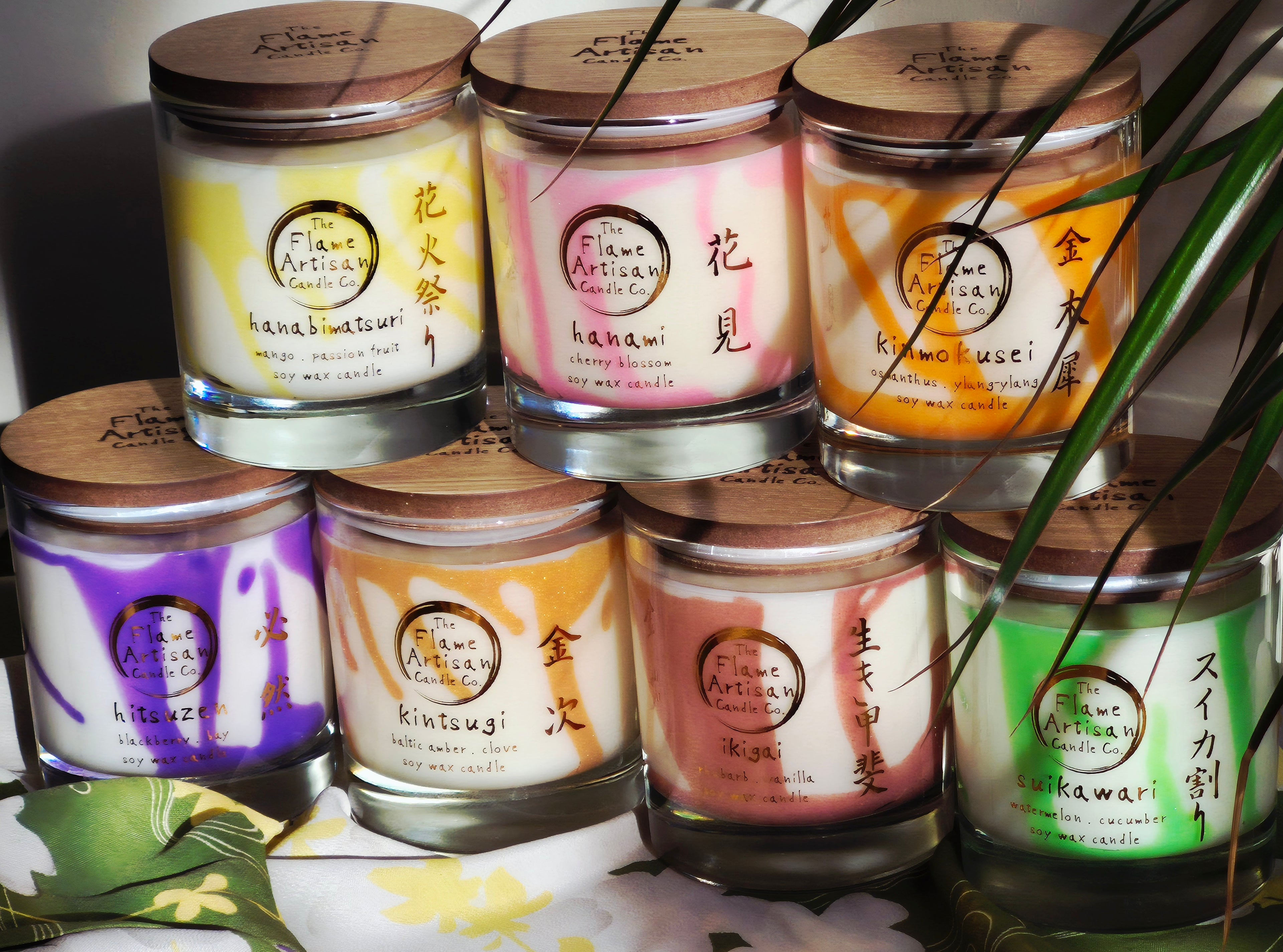 Collection of candles with labelled lids on a white surface.